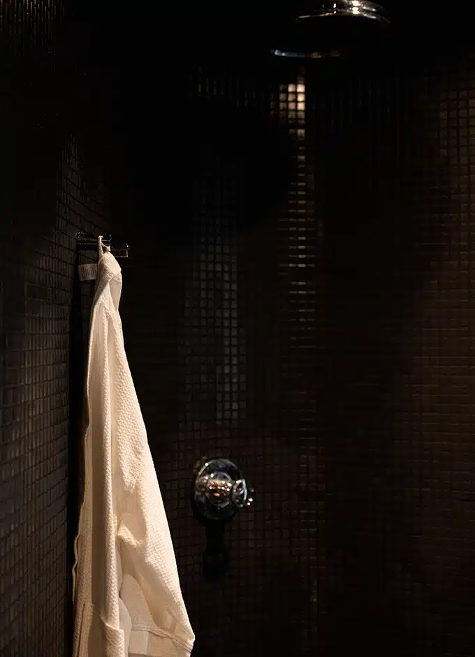 white towel hanging on black tile wall in steam room