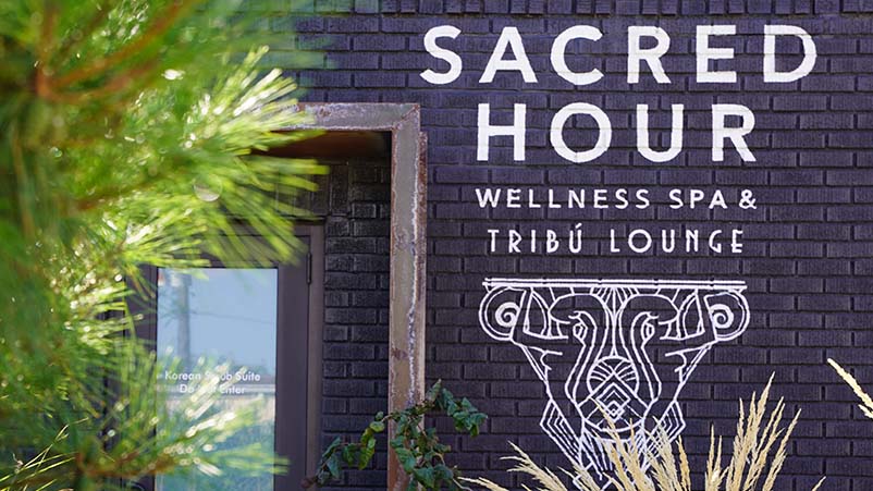 spa parties outside of spa with sacred hour logo on wall