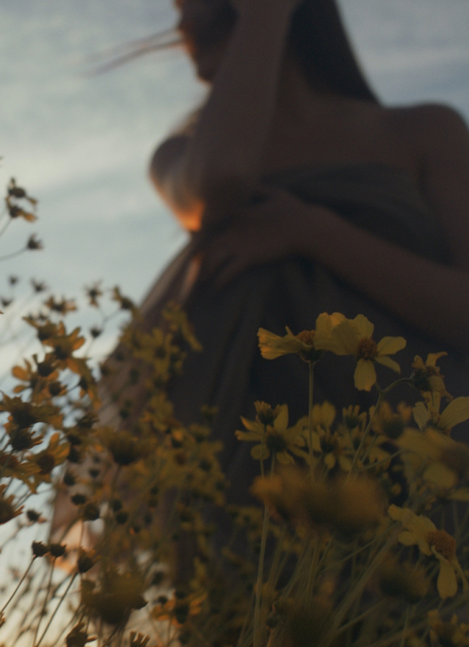 blurred image of woman standing in field of yellow flowers