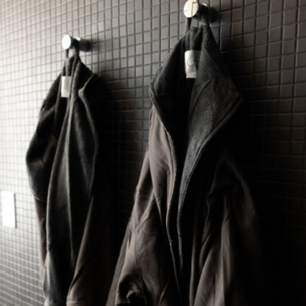 grounding package for 2 black bathrobes hanging on black tiled wall
